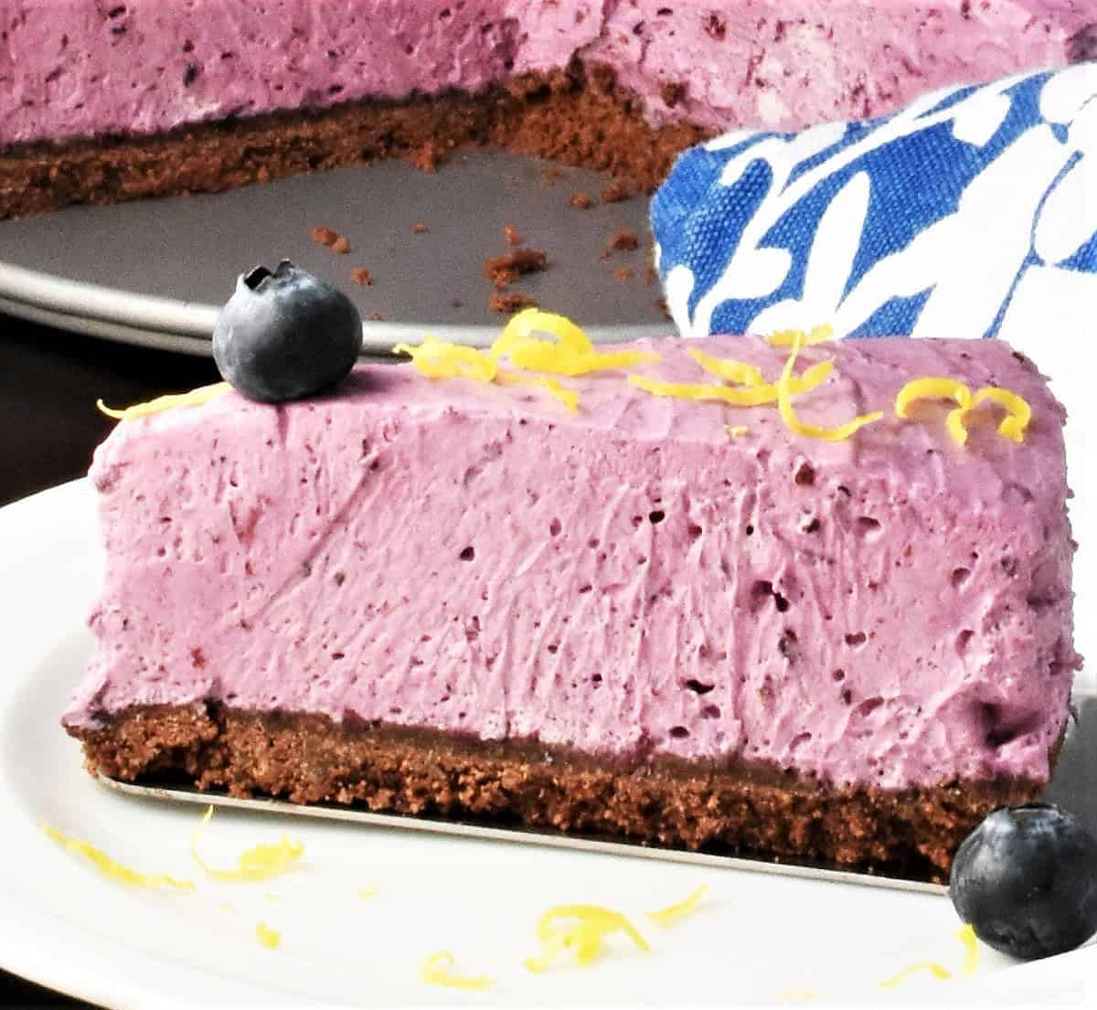 Side view of creamy no-bake cheesecake slice with blueberries on plate.