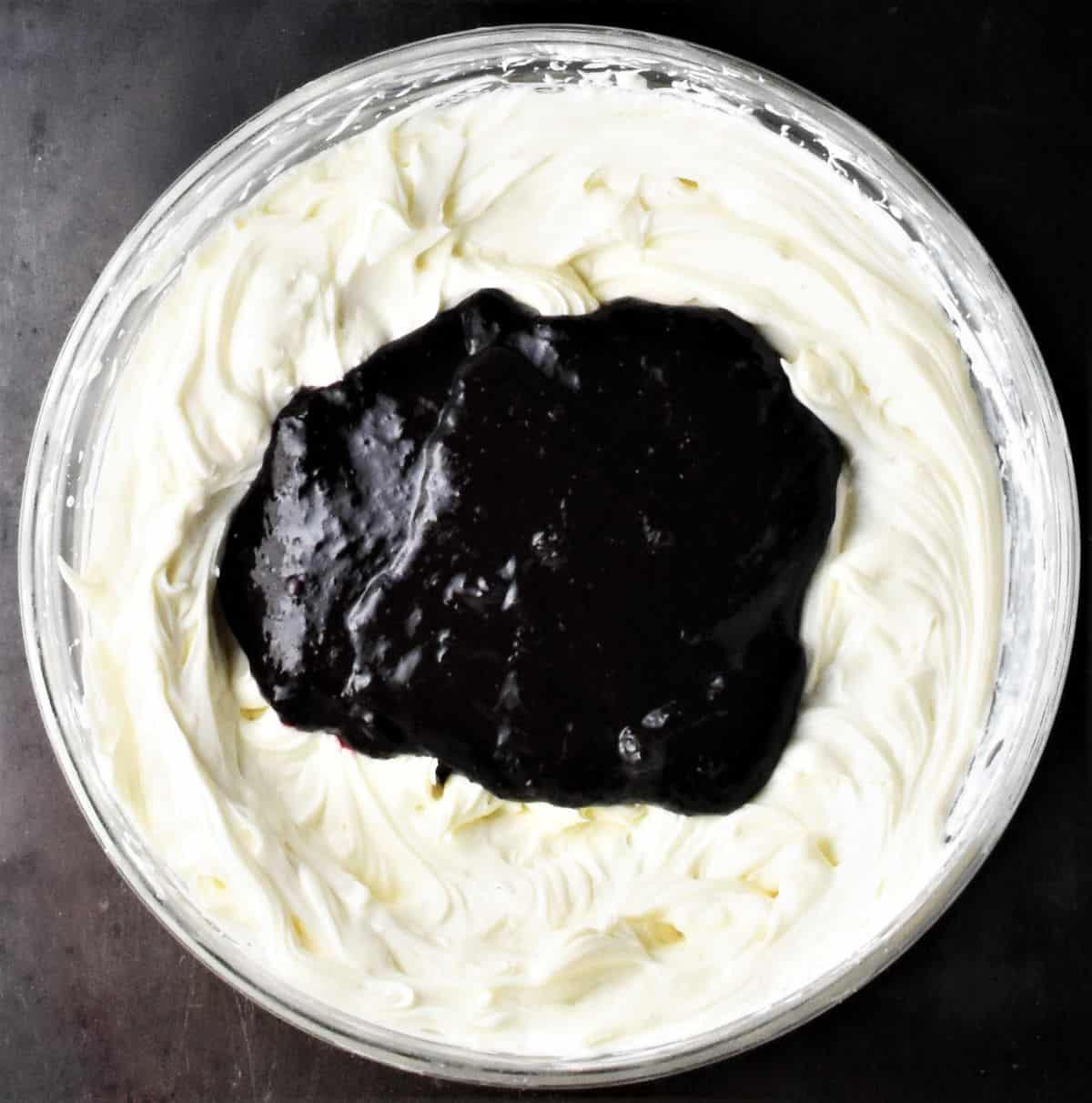 Creamy mixture with blueberry sauce in bowl.