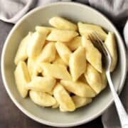 Top down view of pierogi dumplings in bowl with spoon.