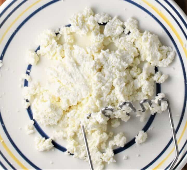 Top down view of twarog cheese in bowl with potato masher.