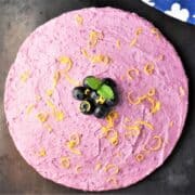 Top down view of round blueberry cheesecake garnished with lemon zest and fresh blueberries.