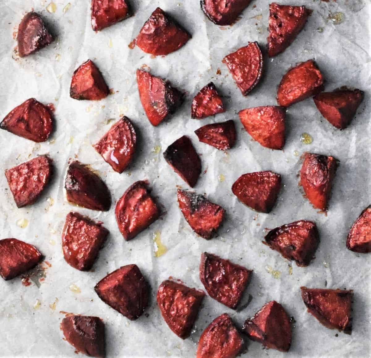 Roasted beetroot pieces on top of parchment.