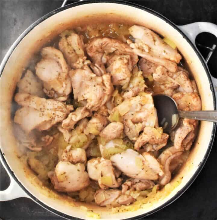 Chicken pieces in large pot with spoon.