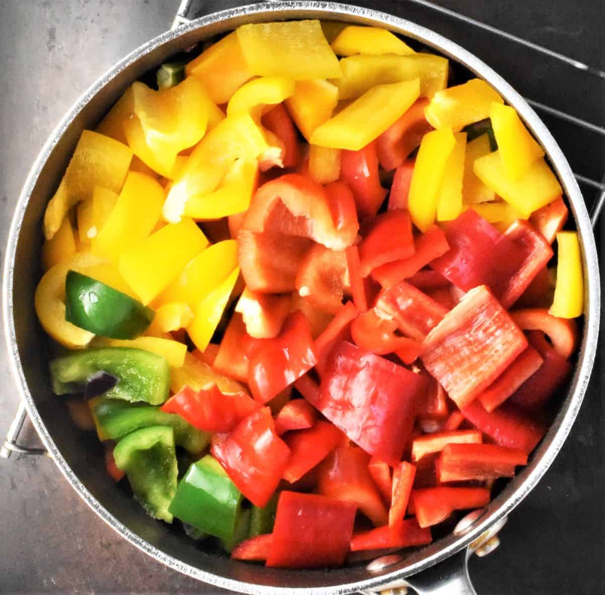 Red, yellow and green chopped peppers in pot.