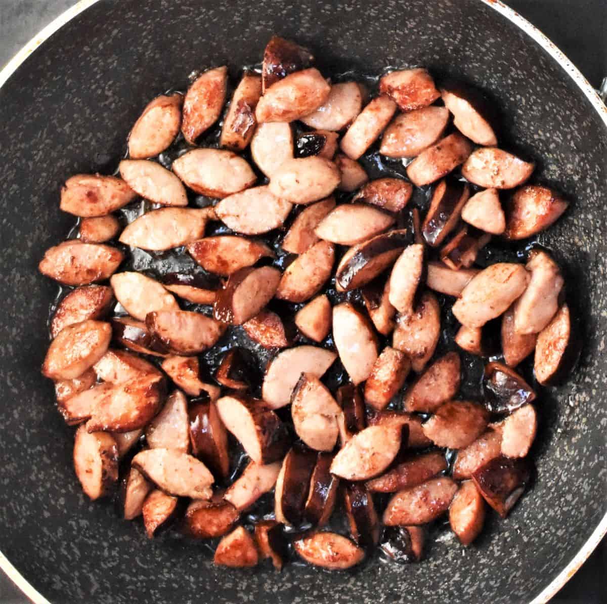 Chopped sausage in large pan.