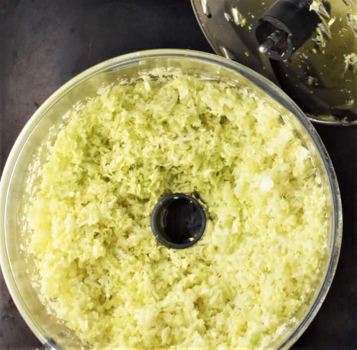 Shredded cabbage in food processor bowl.