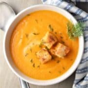 Top down view of creamy cabbage soup with croutons in white bowl.