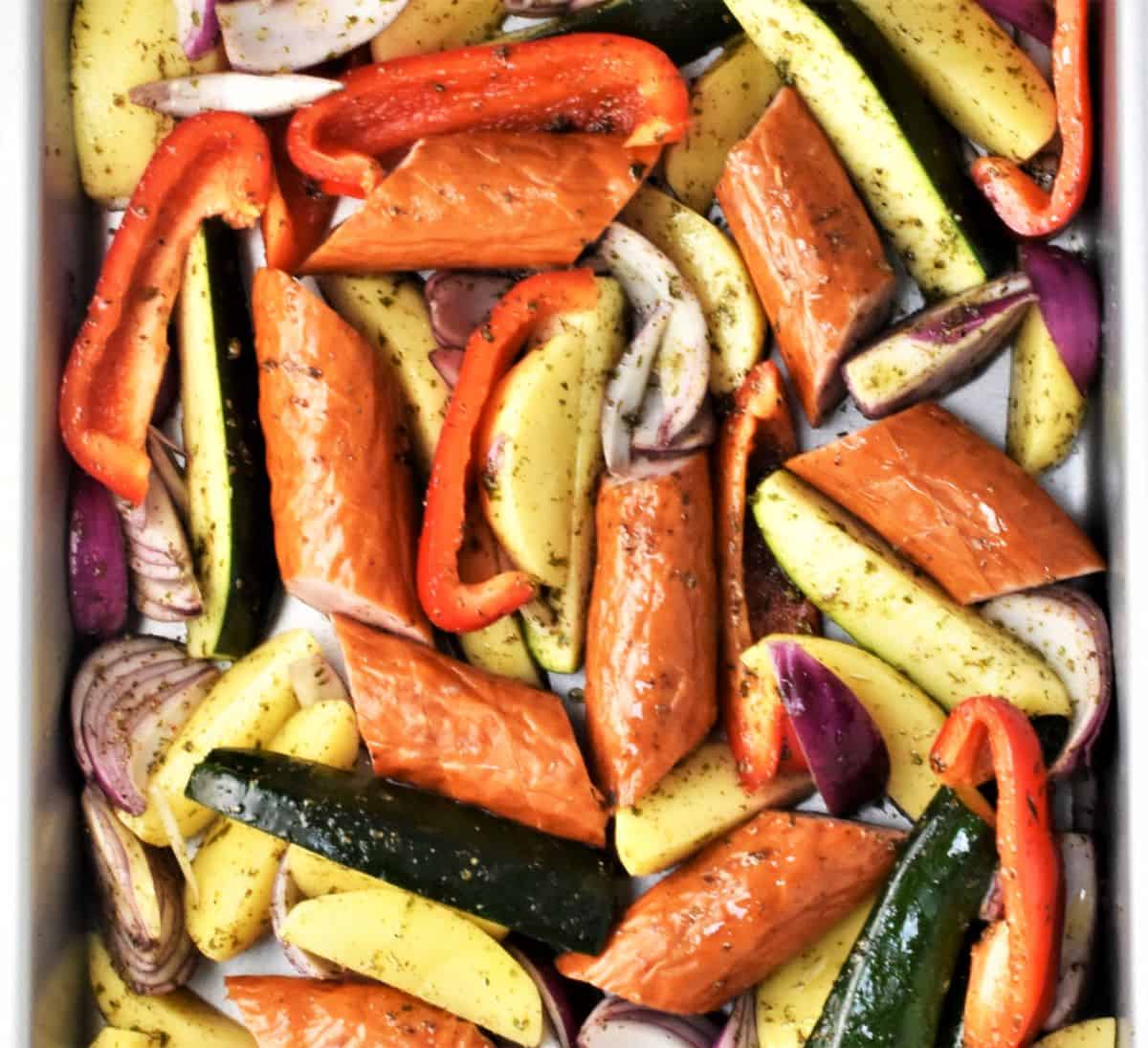 Pieces of kielbasa and vegetables in large tray.