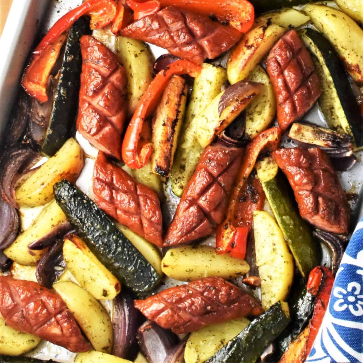 Baked kielbasa and vegetables on top of large sheet.