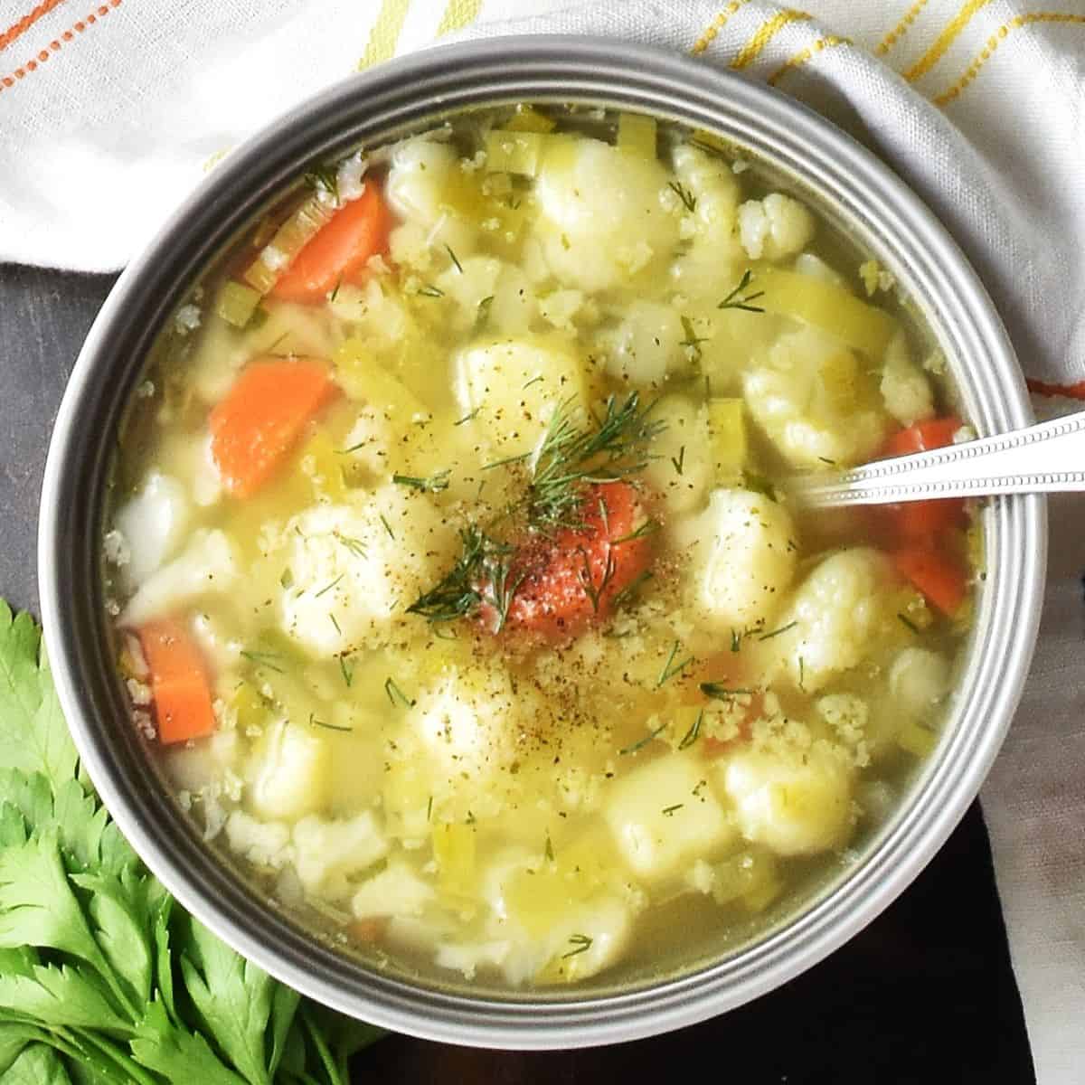 Top down view of Polish cauliflower soup in grey bowl with spoon.