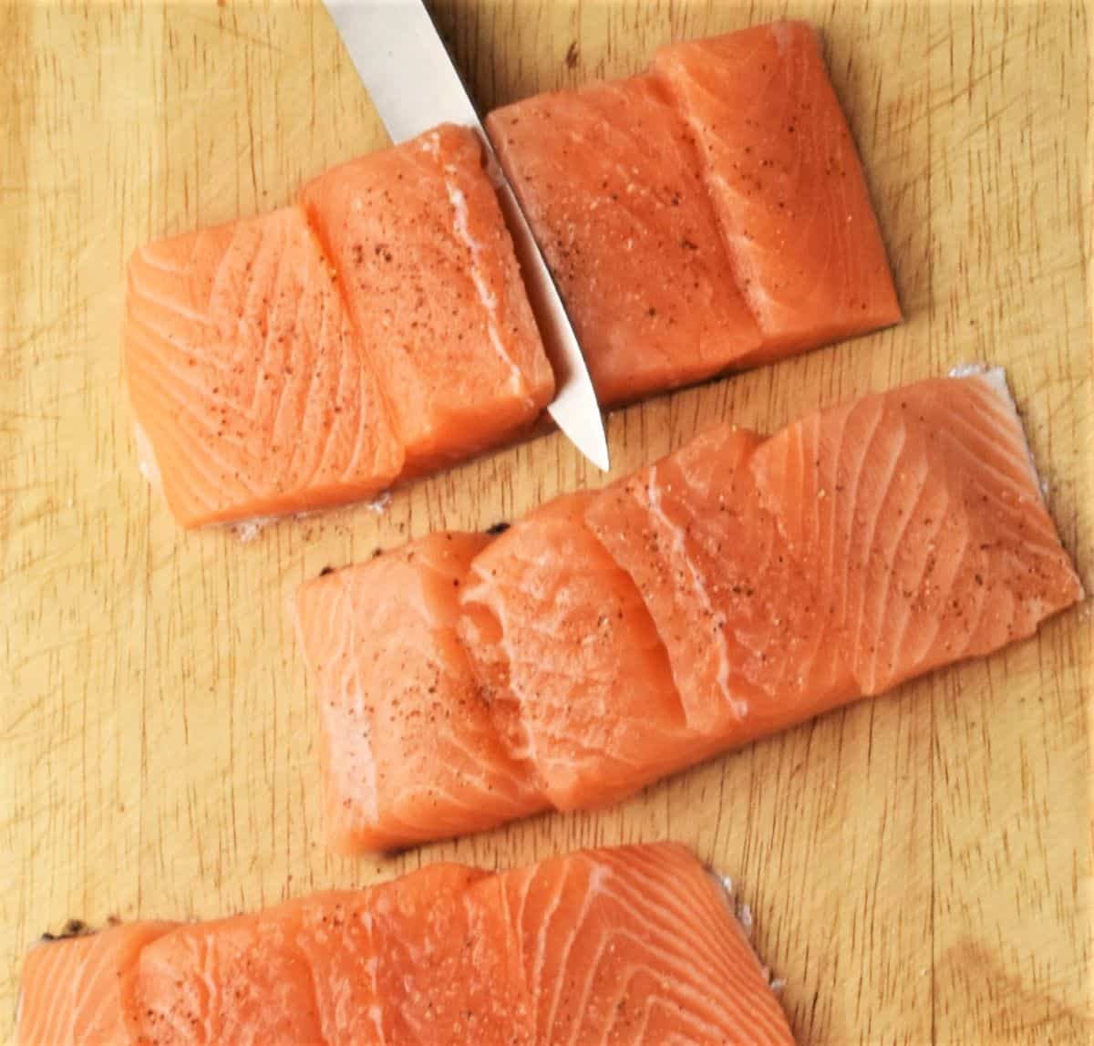 Top down view of hasselbacking salmon fillets with knife.