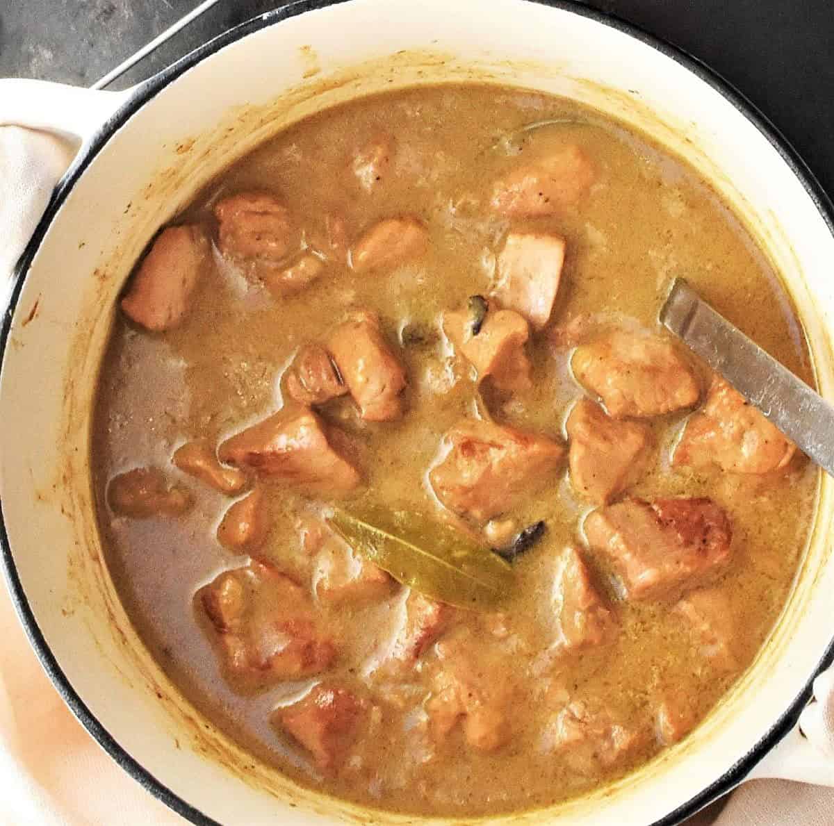 Top down view of Polish pork goulash stew with thick gravy in white pot.