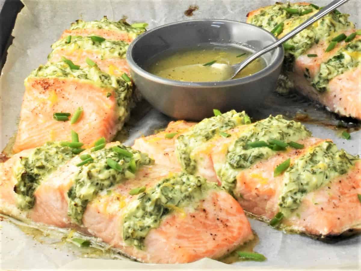 Side view of spinach filled hasselback salmon fillets and dressing.