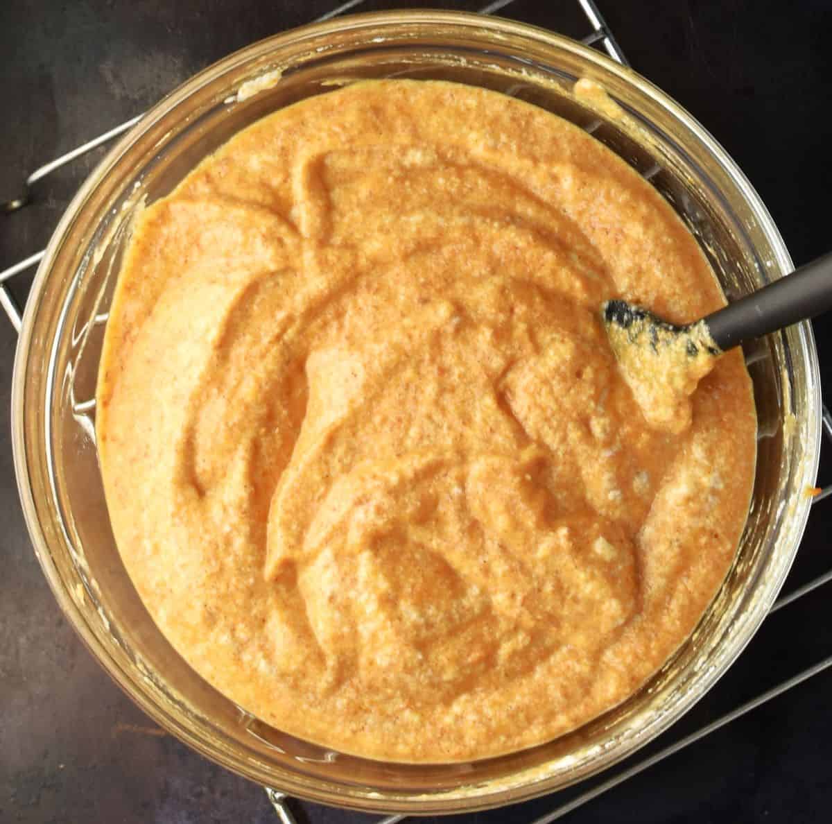Healthy pumpkin pancake batter in mixing bowl with black spatula.