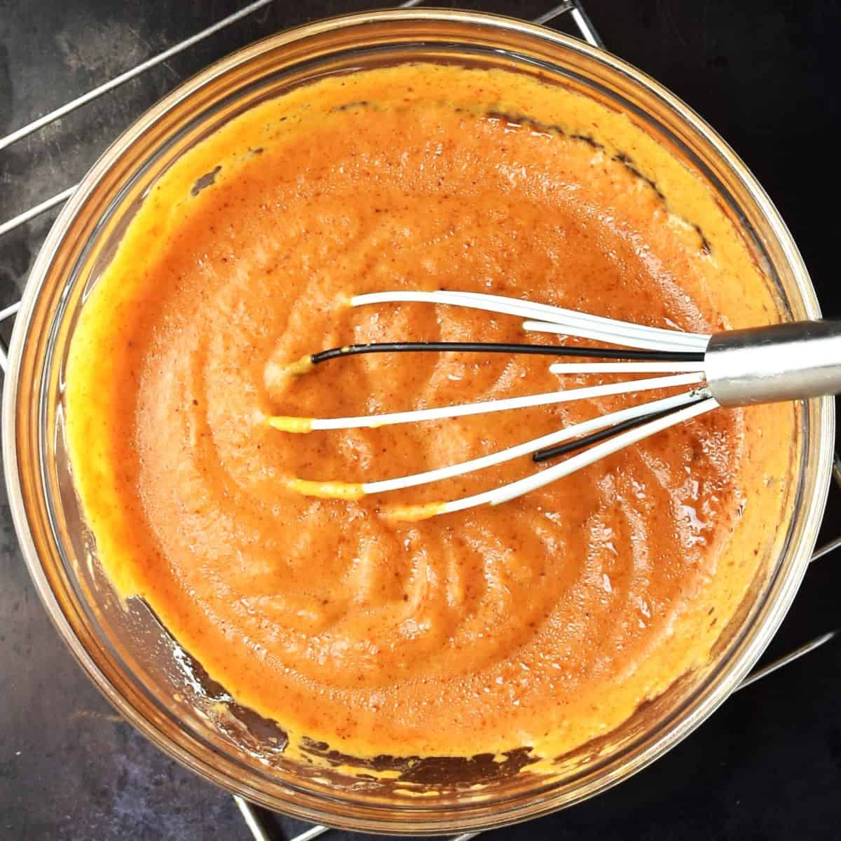 Pumpkin pancake batter without flour in mixing bowl with whisk.