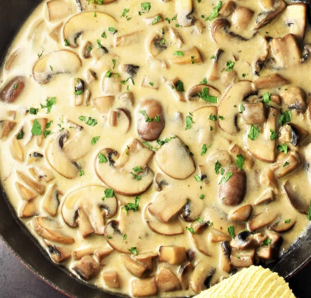 Partial view of mushroom and sour cream sauce in shallow pan.