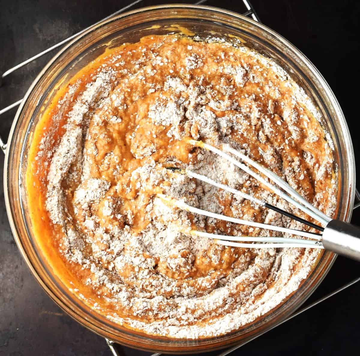 Stirring flour into pancake batter with whisk.