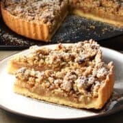 Side view of apple crumble tart slices on white plate.