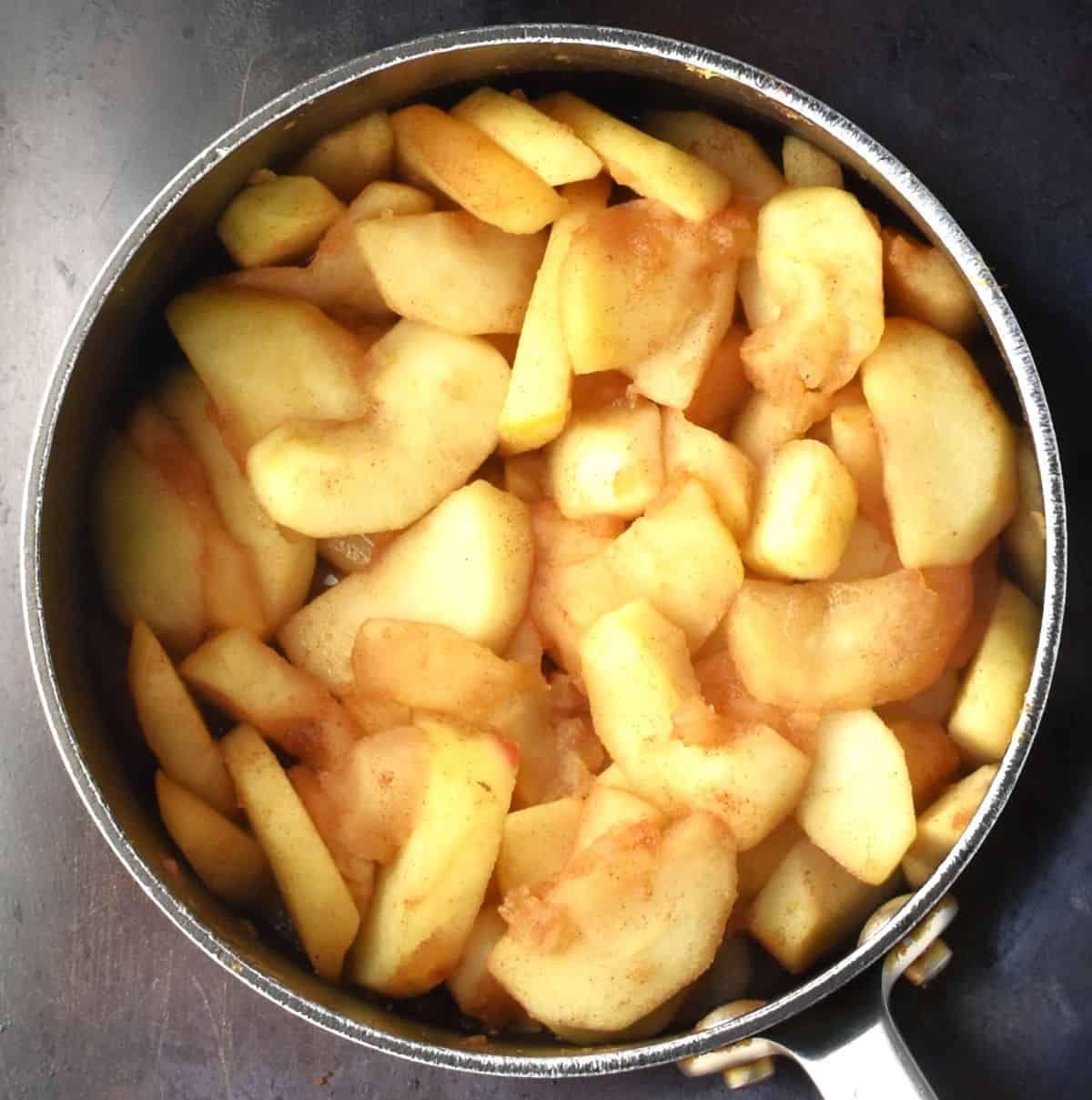 Top down view of partially cooked apple slices in pot.