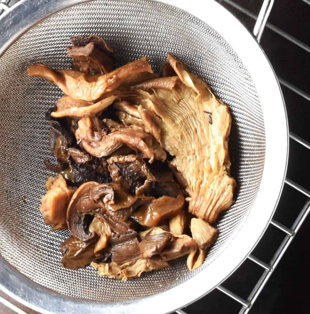 Cooked wild mushrooms in strainer.