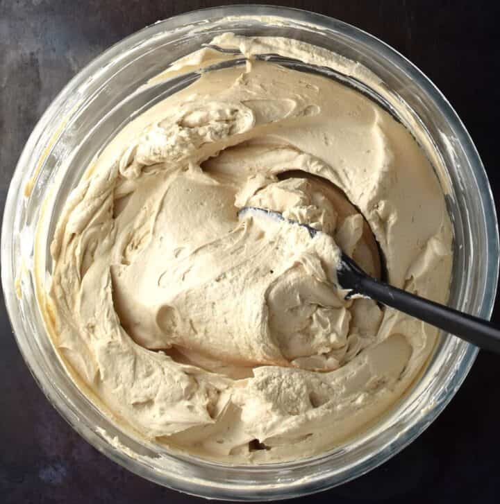 Thick frosting mixture with spatula in bowl.