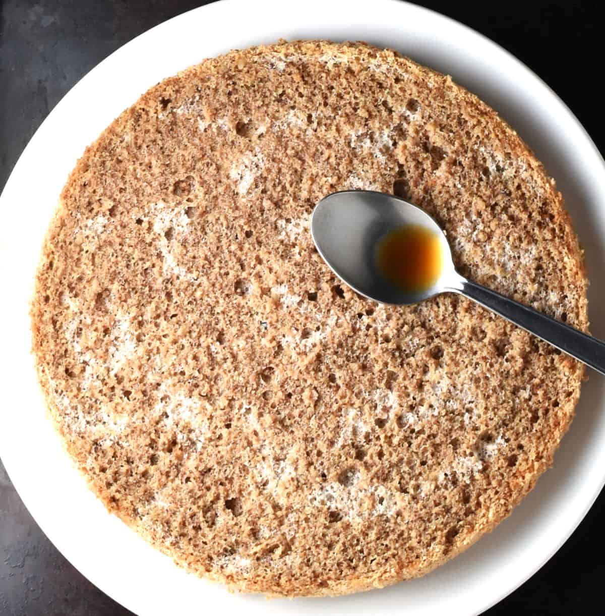 Infusing sponge layer with coffee and spoon on top.