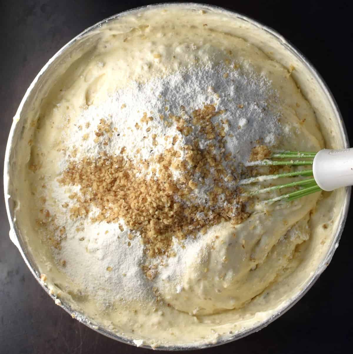 Walnut torte sponge batter in bowl with whisk.