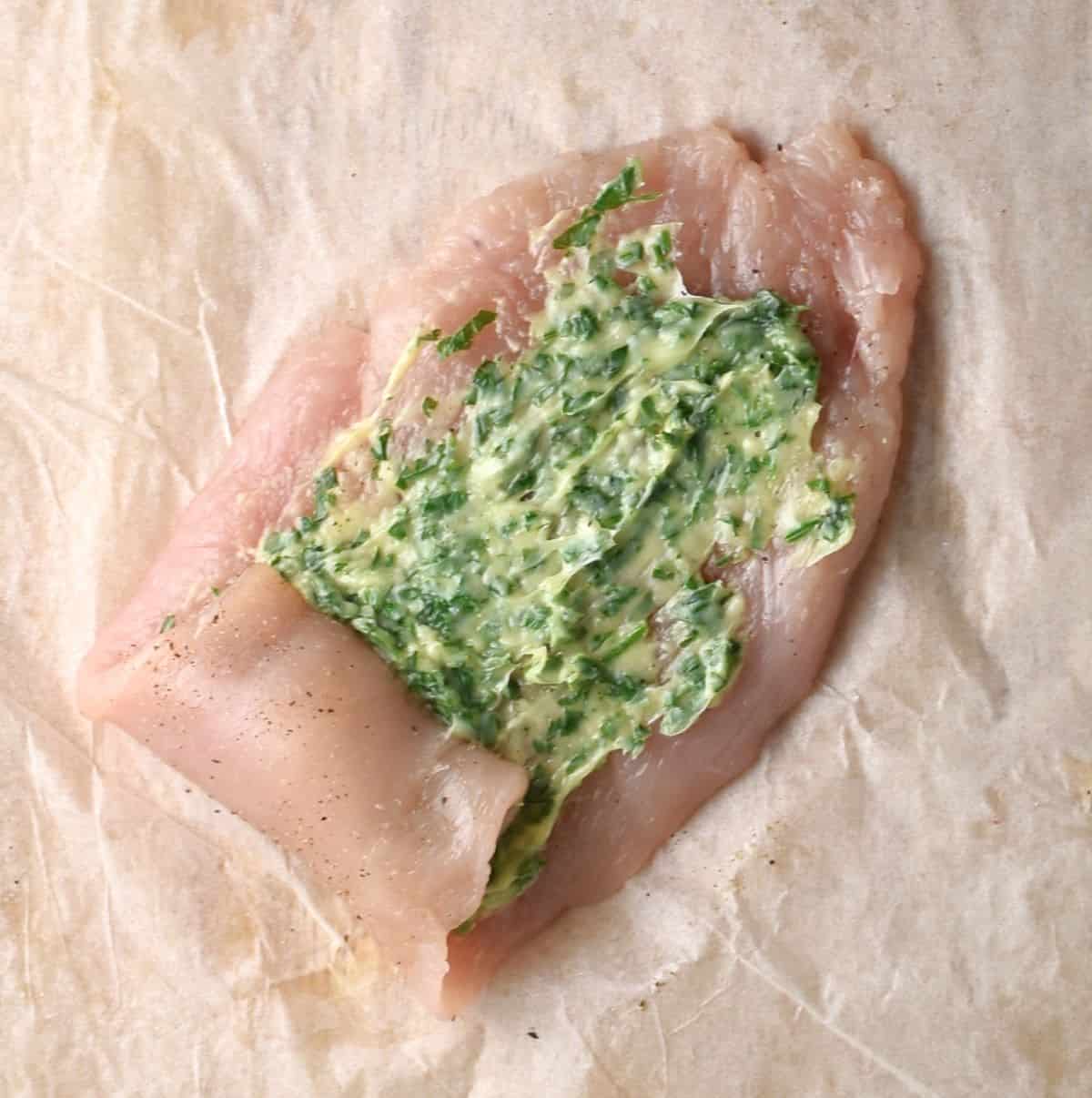 Rolling chicken with parsley and butter inside.