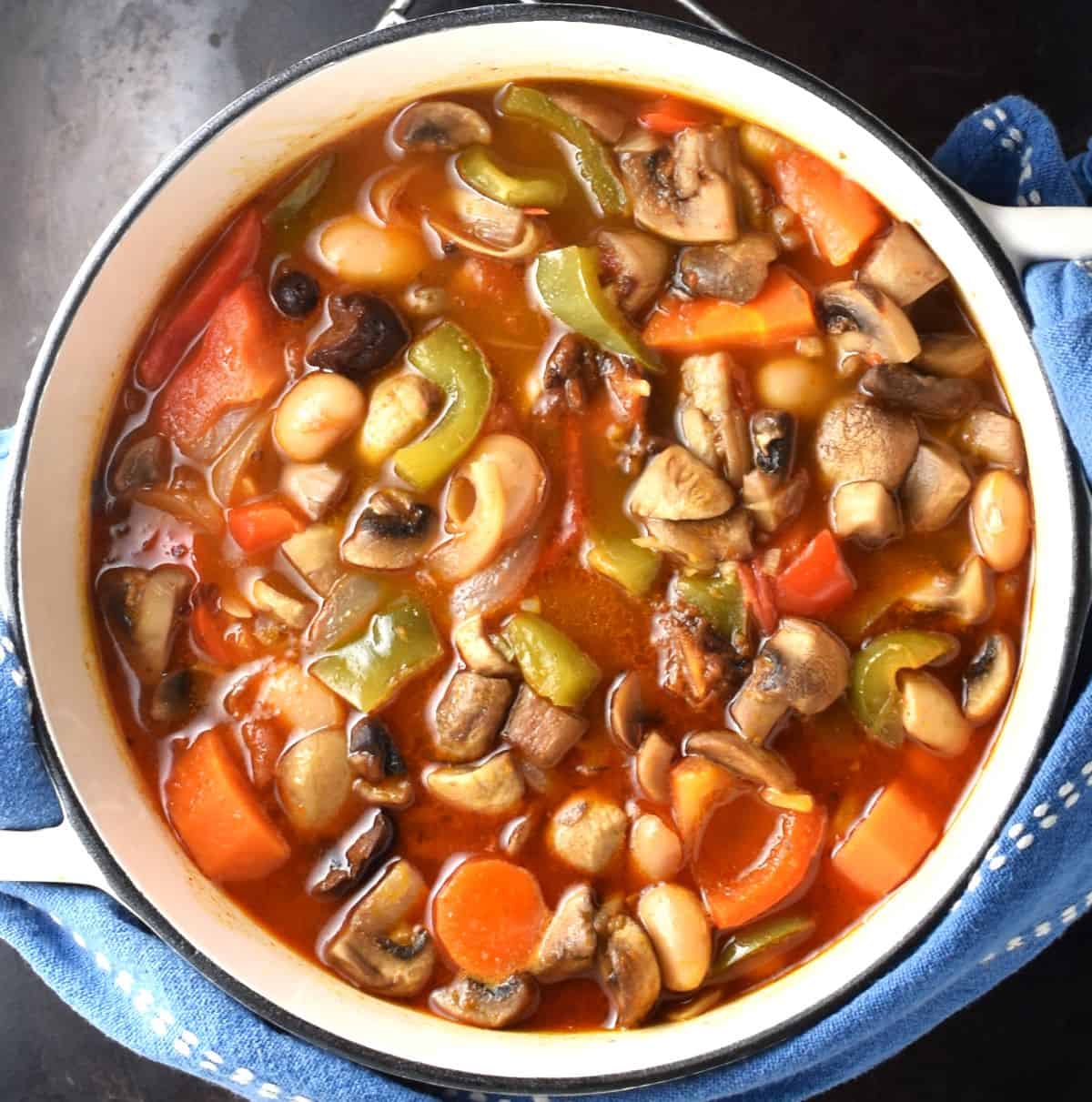 Top down view of goulash with vegetables in white pot.