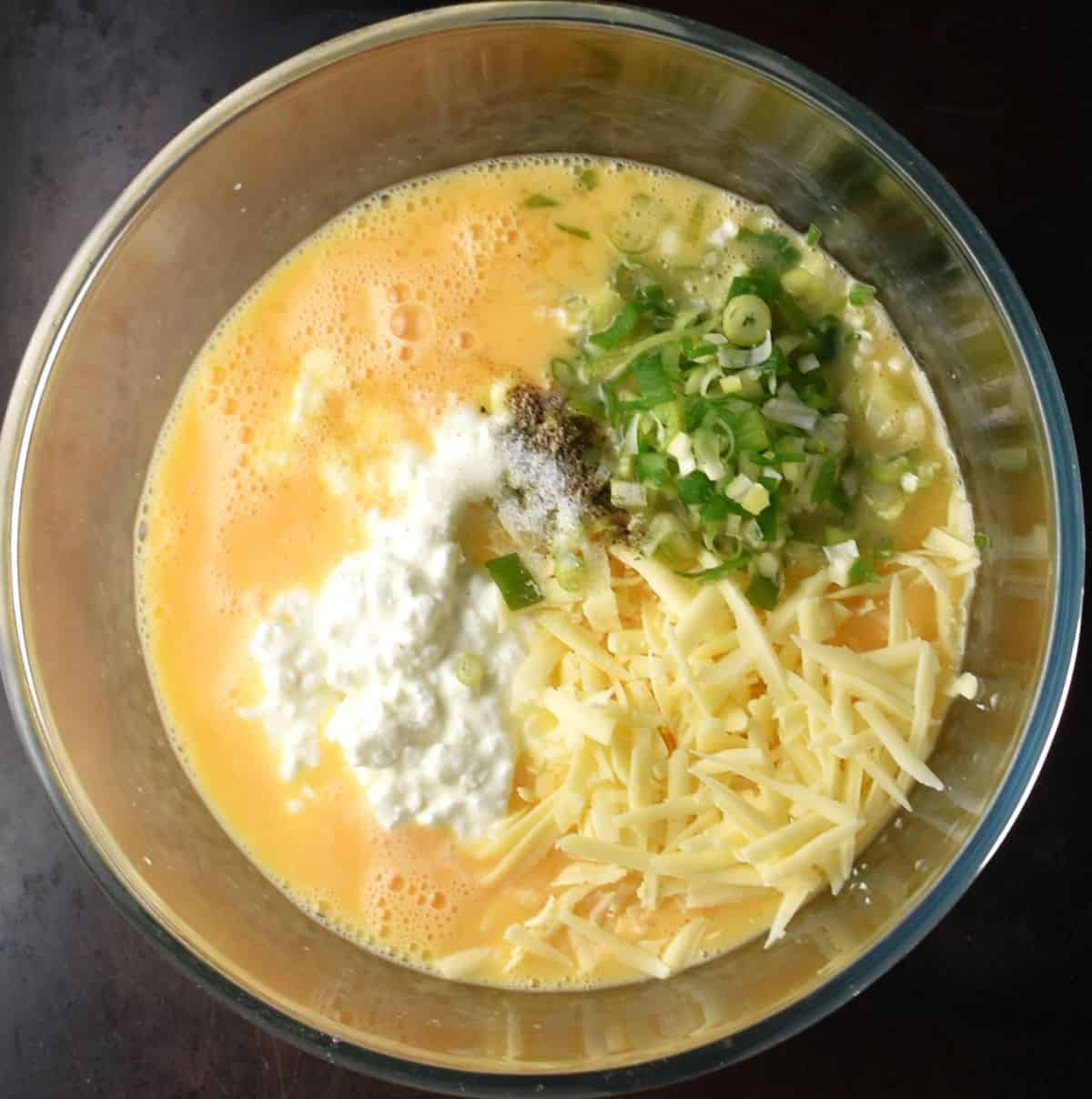 Cottage cheese egg muffin batter ingredients with whisk in bowl.