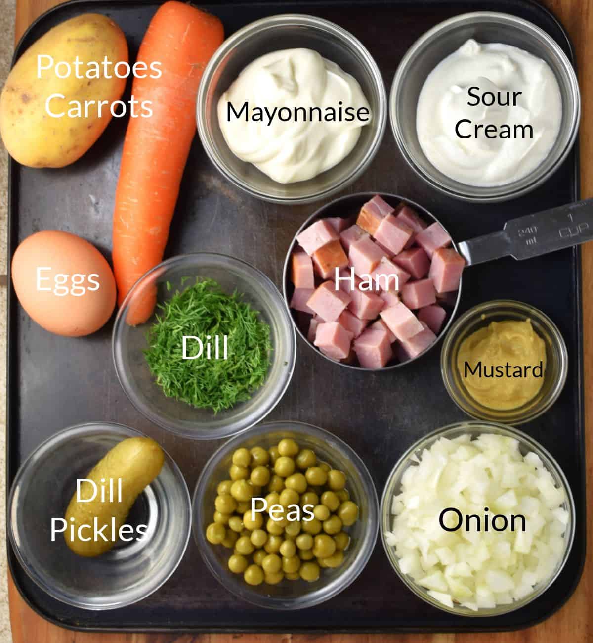 Top down view of ingredients for making Russian Olivier salad in individual dishes.