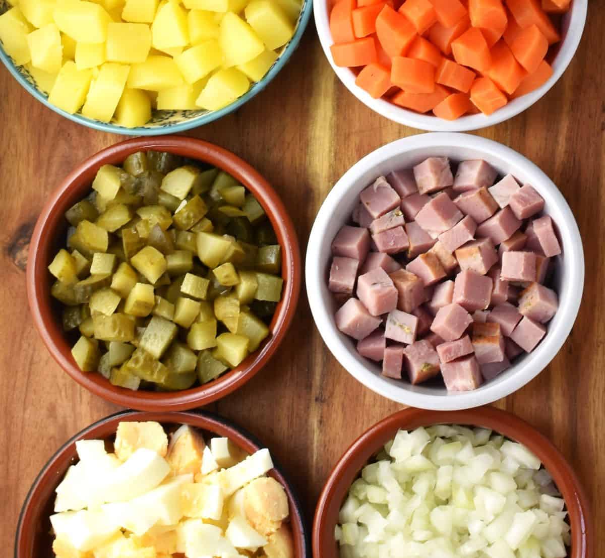 Top down view of cubed vegetables for Russian salad in individual dishes.