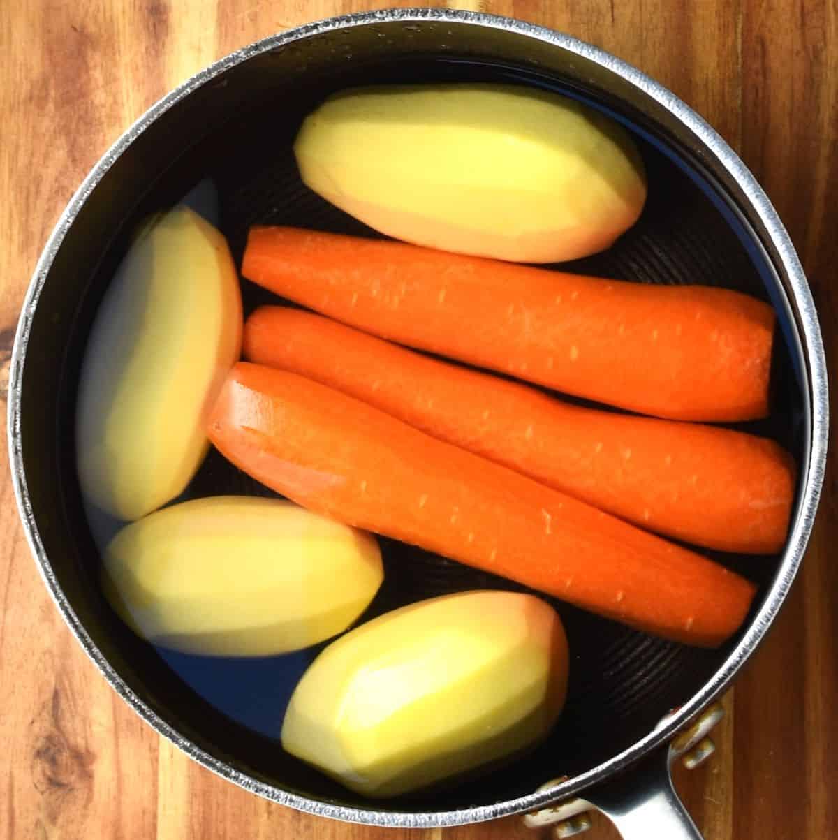 3 peeled carrots and 4 potatoes in pot with water.