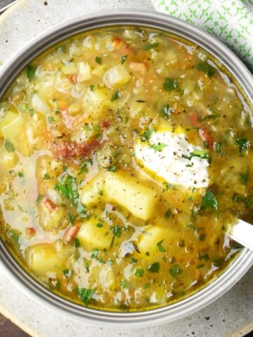 Top down view of Polish potato soup in bowl with spoon.