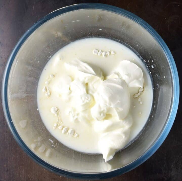 Top down view of milk, flour and sour cream in glass bowl.