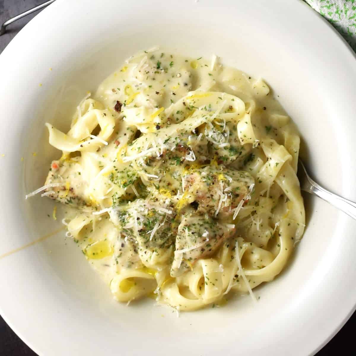 Top down view of sour cream chicken with pasta in white bowl.