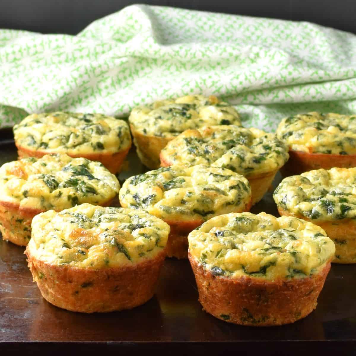 Side view of spinach egg muffins with green cloth in background.