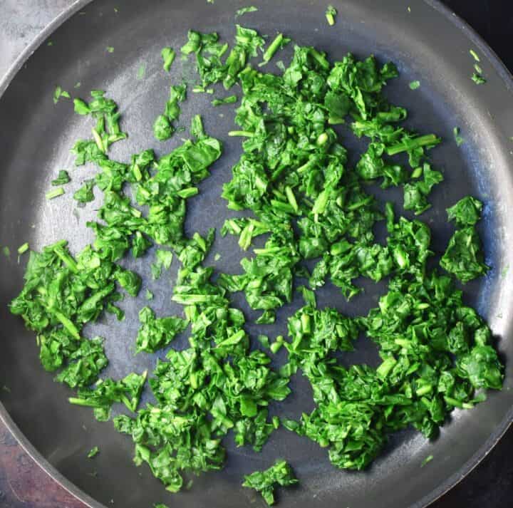 Wilted fresh spinach in large pan.