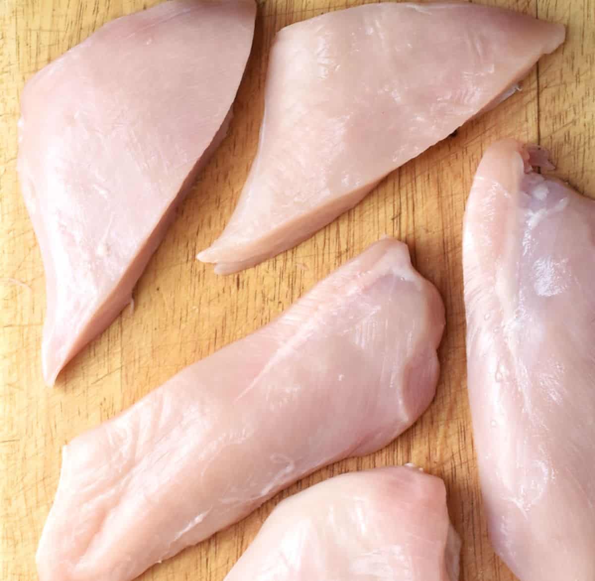 Chicken breast strips on top of cutting board.