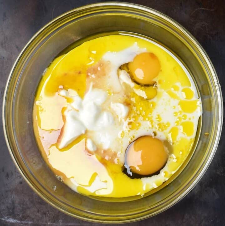 2 eggs, yogurt and oil in glass mixing bowl.