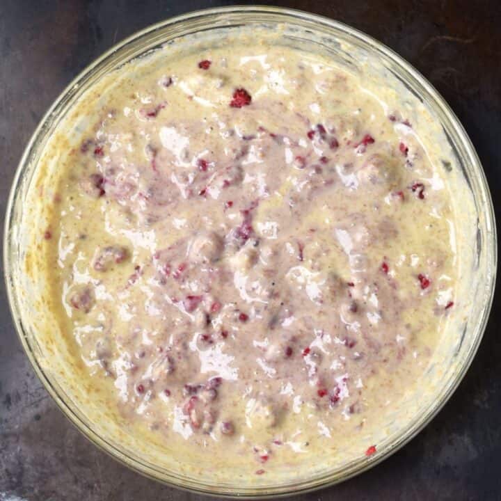 Top down view of raspberry pancake batter in glass bowl.