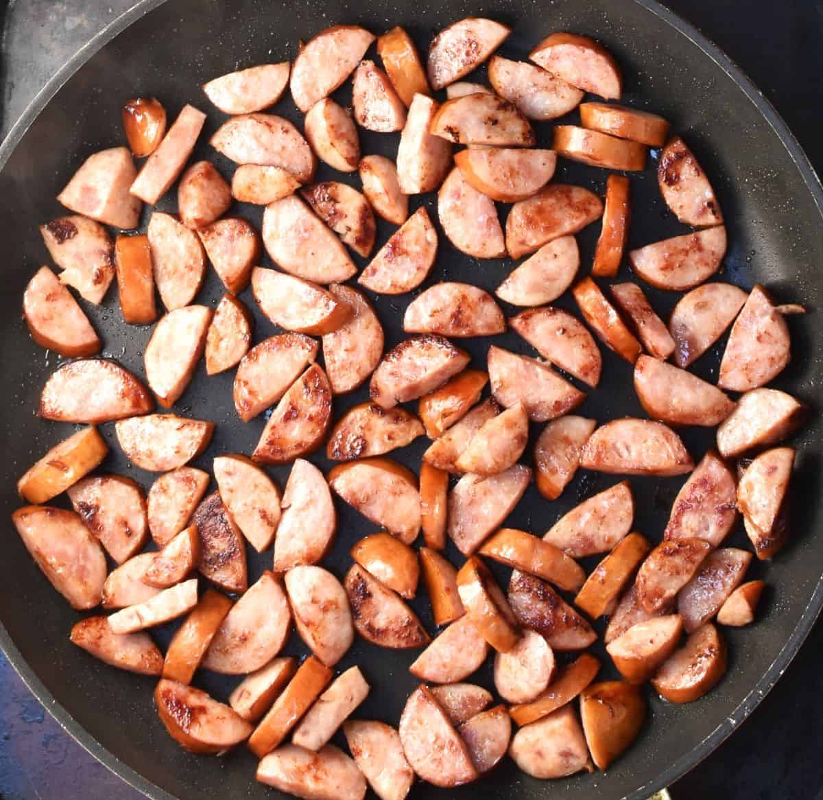 Pieces of kielbasa browned in large pan.