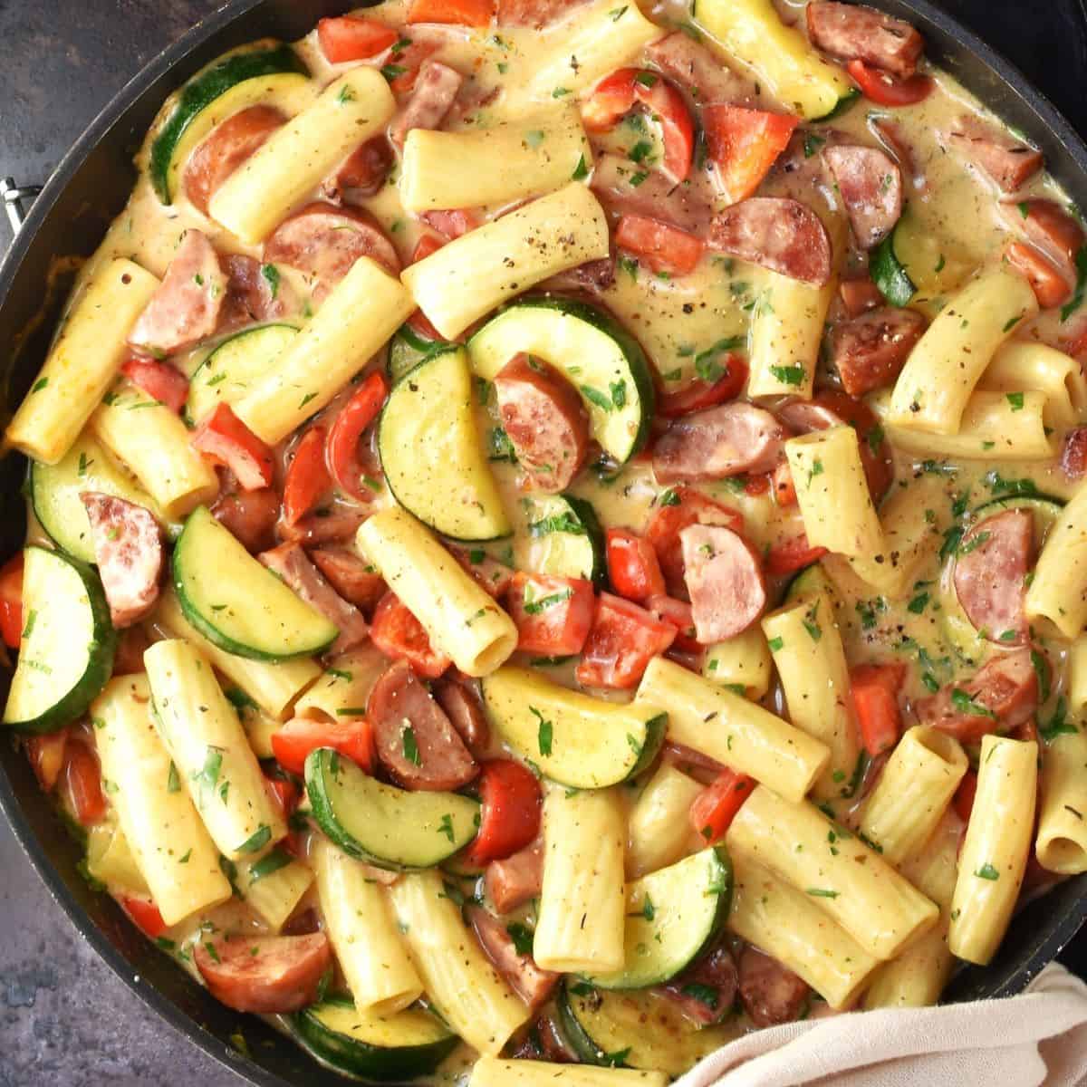 Top down view of kielbasa pasta with vegetables in large pan.
