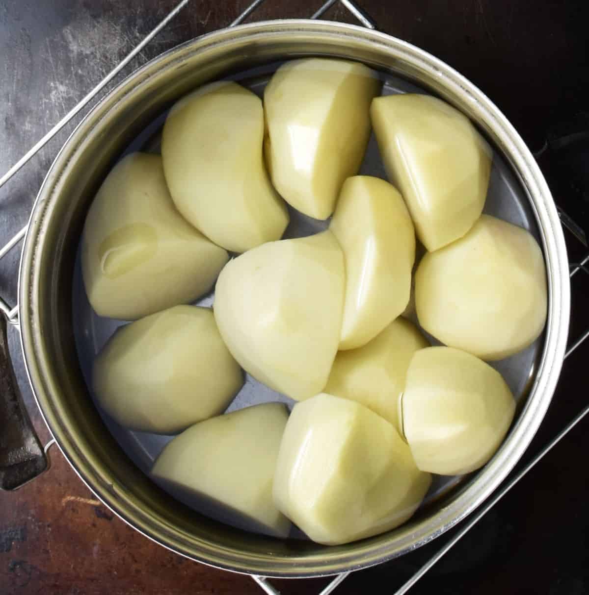 Peeled potatoes in pot with water.
