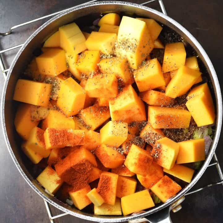 Top down view of cubed butternut squash and paprika in pot.