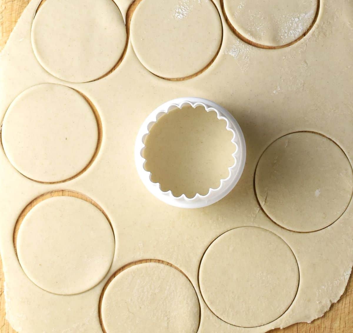 Top down view of rolled out koldunai dough with round shapes and cookie cutter.