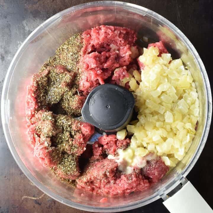 Top down view of koldunai filling ingredients in food processor bowl.