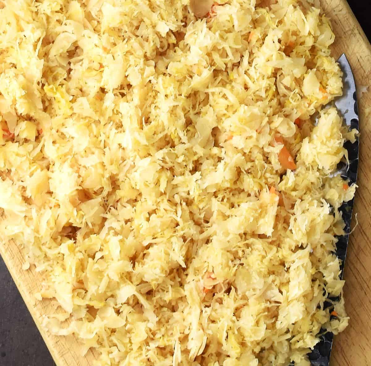 Chopped sauerkraut on top of board with knife.