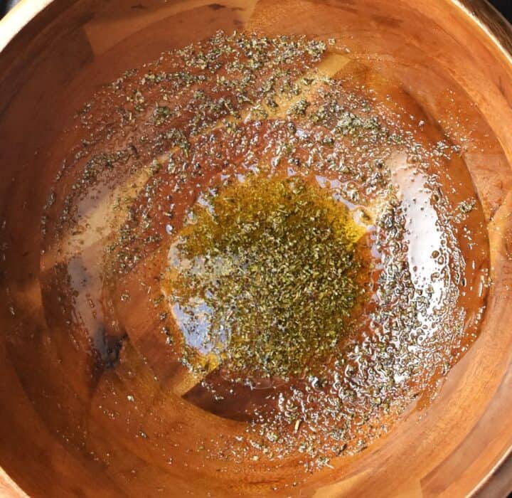 Top down view of seasoning and oil in large wooden bowl.