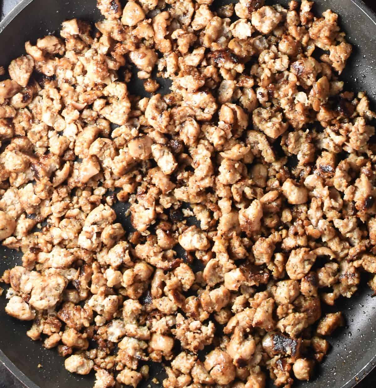 Crumbled sausage browning in pan.